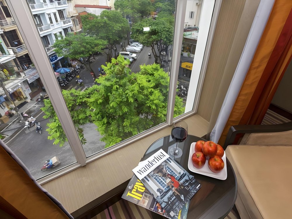 View from an upper-floor window down onto a tree-lined Hang Bong Street, with motorbikes parked along the pavement